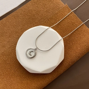 Silver stainless steel snake chain necklace featuring a crescent moon shell pendant on a stand