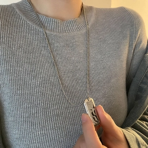 Men's silver hexagonal pendant necklace with wave texture on a grey knit sweater