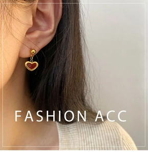 Close-up of red heart earrings with gold trim worn by a model in a minimalist style