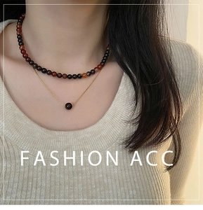 Détail d'un collier double rang avec perles d'agate rouge et chaîne dorée sur un mannequin