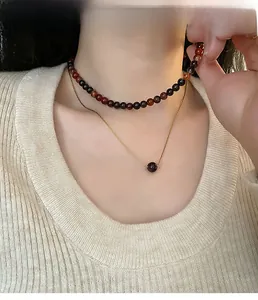 Détail d'un collier double rang avec perles d'agate rouge et fine chaîne dorée