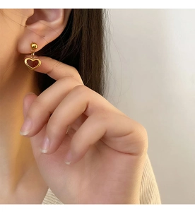 Close-up of elegant red heart drop earrings with gold studs worn by a female model