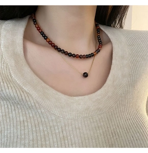 Collier double rang avec perles rouge foncé et chaîne dorée en vue détaillée