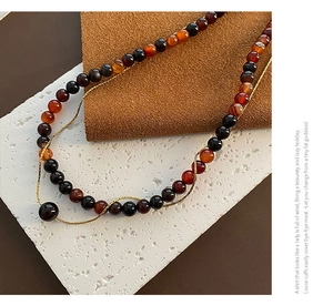 Détail du collier double rang avec perles d'agate rouge et fine chaîne dorée