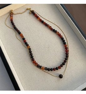 Détail d'un collier double rang avec perles d'agate rouge et chaîne dorée