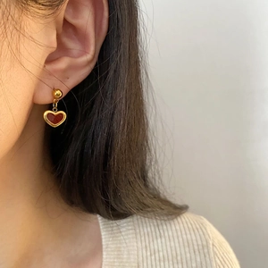 Elegant gold earrings with red heart pendants shown on a model for a minimalist look