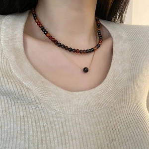 Collier double rang en or avec perles d'agate rouge foncé porté par un mannequin