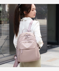 Vue latérale du sac à dos élégant en nylon mauve avec détails dorés en milieu urbain