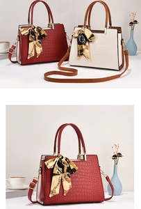 Detail van elegante draagtassen met krokodillenpatroon in bordeaux en beige met zijden sjaal