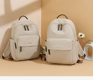 Close-up of lightweight nylon backpack featuring a golden logo and brown handle detail