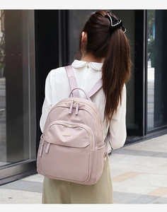 Photo en extérieur d'un sac à dos rose poudré en tissu Oxford avec des zips dorés chic