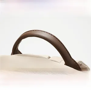 Detail of off-white oxford fabric with durable brown faux leather handle and neat stitching