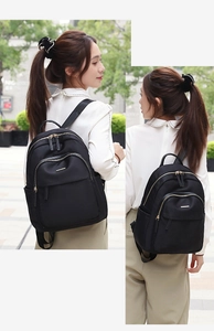 Détail d'un sac à dos noir en nylon avec fermetures éclair dorées et poche latérale