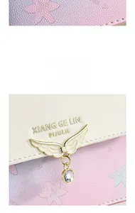 Détail du cuir rose avec motif floral gaufré et pendentif en forme d'aile dorée