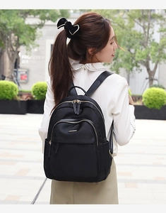 Photo en extérieur d'une femme portant un sac à dos noir en tissu Oxford avec poches zippées