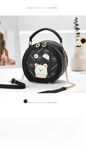 Detailed close-up of a round black bear print bag with textured leather and gold chain
