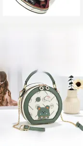 Detail of round cream and green crossbody bag with bear motif and chain strap