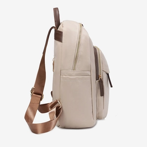 Détail d'un sac à dos en tissu Oxford beige avec fermetures dorées et languettes en cuir