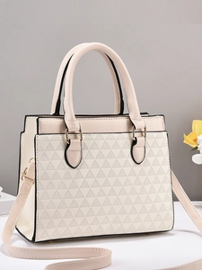 Close-up of cream handbag with geometric triangle embossing and gold hardware details