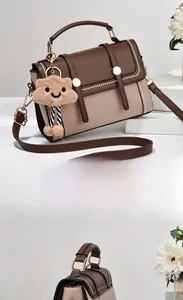 Détail du sac à bandoulière bicolore avec rabat marron et boucle dorée élégante