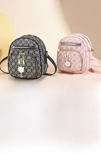 Detail showing vintage print crossbody bag with multiple zippers and cat charm