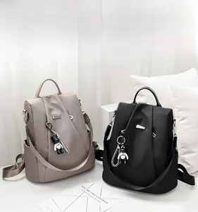 Detail view of khaki and black anti-theft nylon backpacks with teddy bear charms