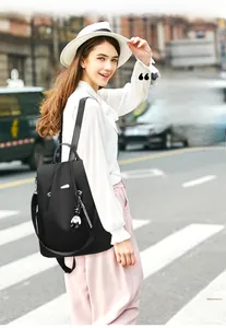 Outdoor shot of a black nylon backpack for women with a cute bear charm pendant