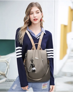 Close-up of gray Oxford fabric backpack with anti-theft design and a cute bear pendant