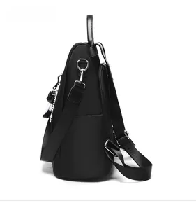 Side view of black Oxford cloth backpack with adjustable straps and cute bear pendant