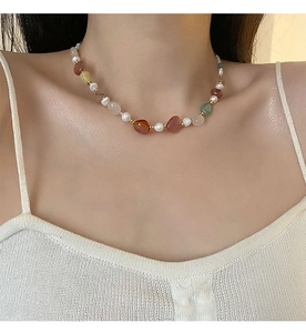 Detail of beaded necklace featuring colorful natural stones and freshwater pearls on model