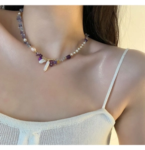 Detail of amethyst and baroque pearl necklace worn on model neck with gold beads