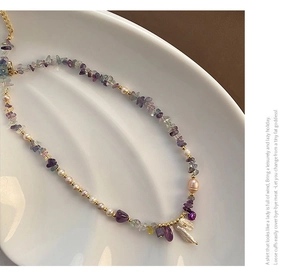 Detailed close-up of amethyst and freshwater baroque pearl beaded necklace on a ceramic plate