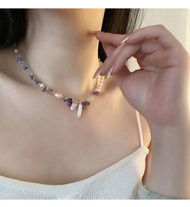 Detail of amethyst and baroque pearl necklace worn by a model on a white sweater