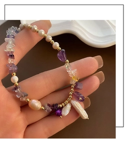 Detail of baroque pearl bracelet with amethyst stones and golden beads on hand