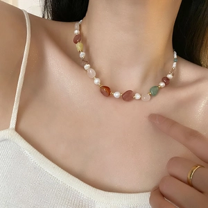 Handmade necklace with natural colored gemstones and freshwater pearls on female neck