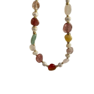 Colorful natural stone and freshwater pearl necklace with gold bead accents on white background