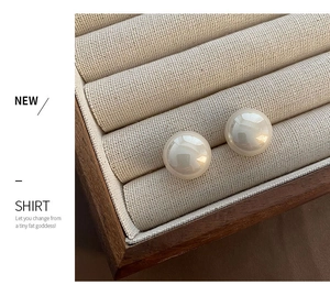 Close-up of elegant large round pearl studs set in a vintage wooden jewelry display box