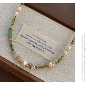 Macro shot of green gemstones and white pearls on a vintage-style handcrafted necklace