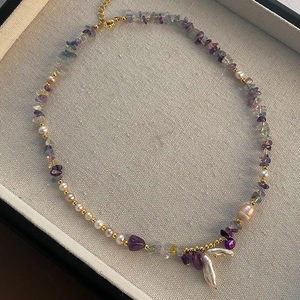 Baroque pearl and amethyst stone necklace set with gold accents on a jewelry tray