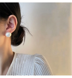 Close-up of elegant large round white pearl earrings on model with titanium steel post