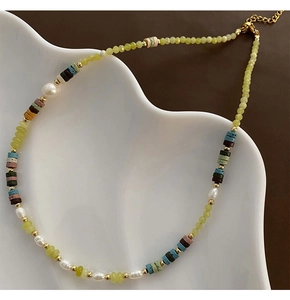 Detail of beaded necklace with peridot, pearls, and colorful volcanic stones on ceramic tray