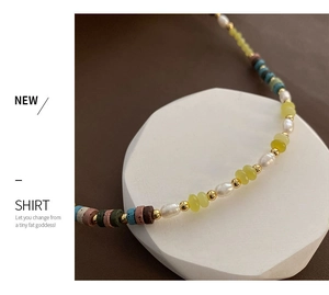Close-up of pearl and peridot beaded necklace on a white geometric display stand