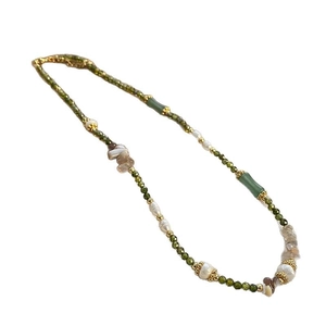 Green beaded necklace with white pearls and bamboo-shaped accents on a white background