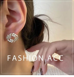 Detail of elegant gold wheat ear earrings featuring marquise crystals and white enamel leaf