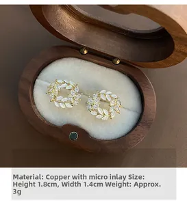 Detailed view of gold wheat ear stud earrings on a beige velvet jewelry display box