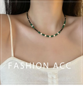 Macro detail of agate and pearl beaded necklace with gold spacers on a model's neck