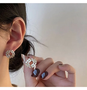 Detailed close-up of wheat ear wreath earrings with gold metal and white enamel inlay