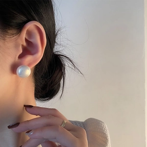 Classic large round pearl earrings in minimalist style worn by model on beige background
