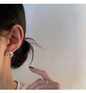 Close-up of elegant gold wheat ear wreath earrings with white petals on model