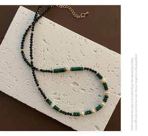 Macro detail of agate pearl necklace with malachite beads on a white travertine stone